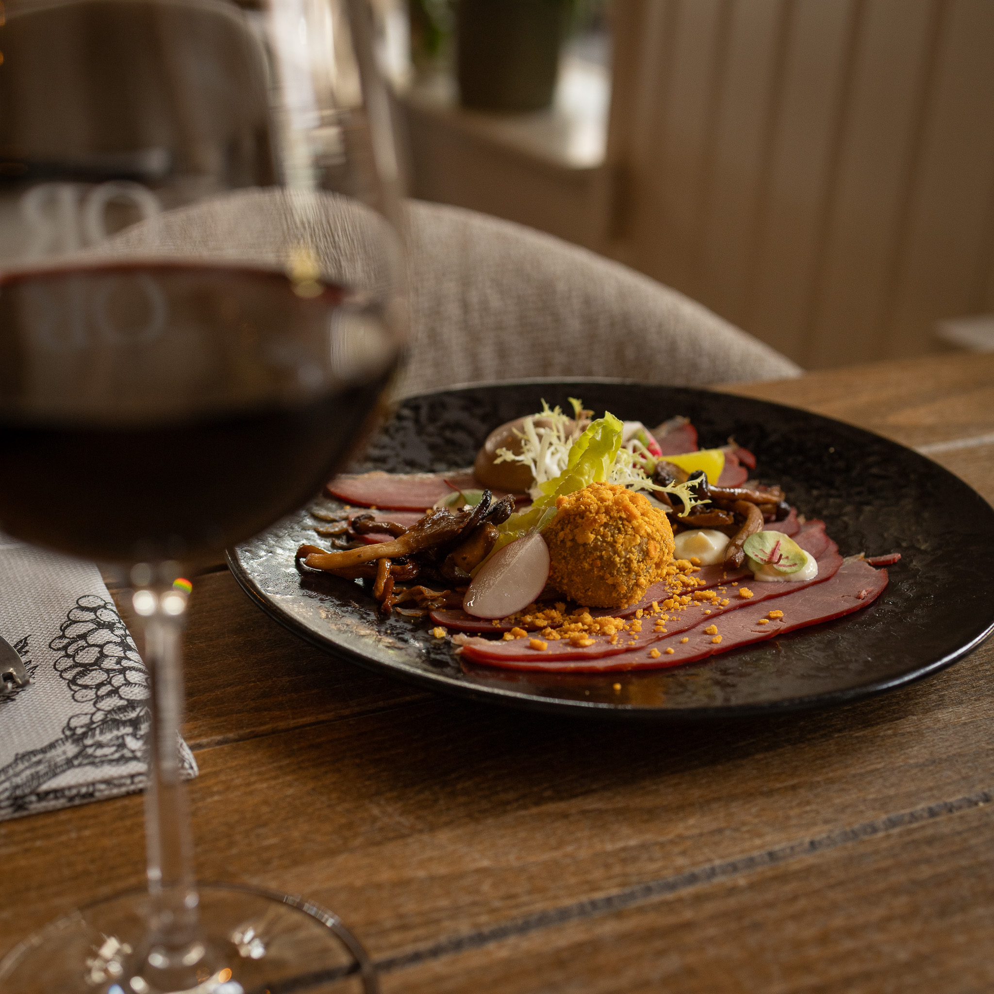 voorgerecht met eend en een glas rode wijn op een net gedekte tafel bij restaurant 't Olde Regthuys